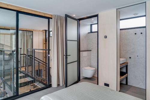 a bedroom with sliding glass doors and a toilet at OplooPark Forrest Villa in Oploo