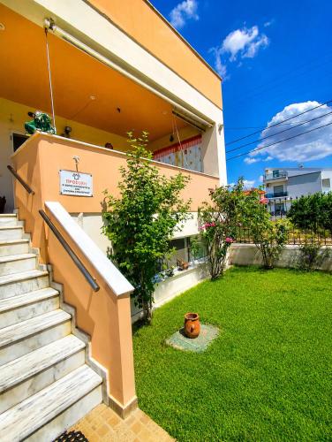 a building with a staircase and a yard with grass at Angela's House in Nea Plagia