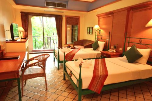 Habitación de hotel con 3 camas, escritorio y mesa. en Pung-Waan Resort & Spa en Kanchanaburi