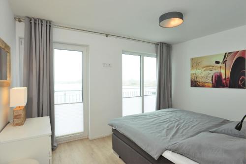 a bedroom with a bed and two large windows at Marina Villa in Olpenitz