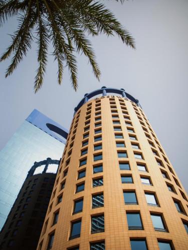 a tall building with a palm tree in the foreground at Rosewood Jeddah in Jeddah