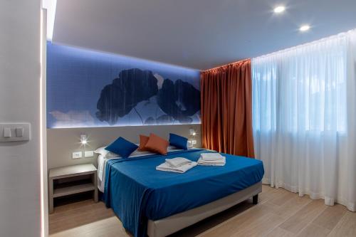 a bedroom with a bed with blue sheets and orange pillows at Hotel Al Sole in Grado