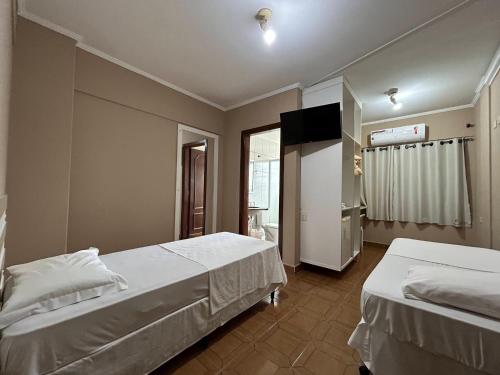 a bedroom with two beds and a television in it at Ibericas Praia Hotel in Praia Grande