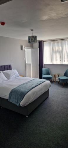 a bedroom with a large bed and two chairs at Moon Tap Hideaway in Bridlington