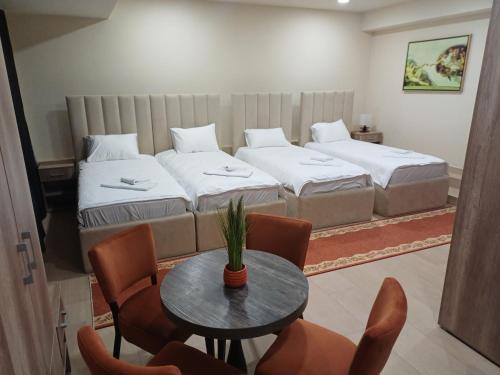 a room with two beds and a table and chairs at Apartmani Nešković Foča in Foča