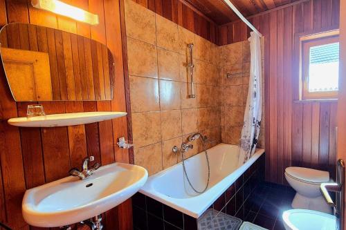 a bathroom with a sink and a tub and a toilet at Ciasa Lovara in Lovara