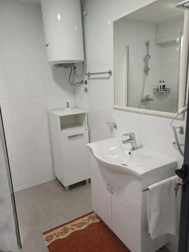 a white bathroom with a sink and a mirror at Apartmani Nešković Foča in Foča