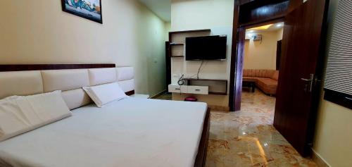 a bedroom with a white bed and a television at hotel celebrations in Jāmb