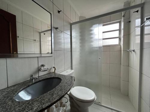 a bathroom with a sink and a toilet and a mirror at Ibericas Praia Hotel in Praia Grande