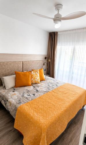 a bedroom with a bed with an orange blanket at Festasol - Apartament Estartit in Torroella de Montgrí