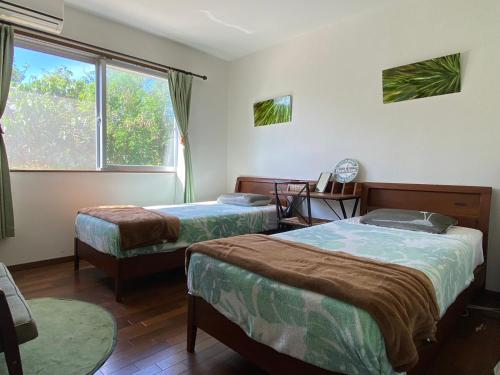 a room with two beds and a window at Beach House Bellissima ! in Yomitan