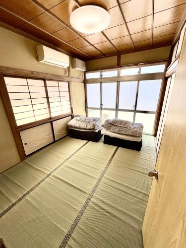 two beds in an empty room with windows at 灯ゲストハウス石巻 in Ishinomaki