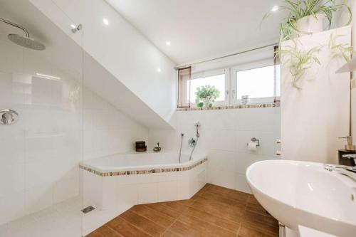 a white bathroom with a sink and a bath tub at Haus Heidi in Freyung