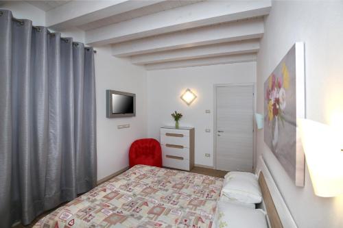 a small bedroom with a bed and a red chair at Venice Loft in Marghera