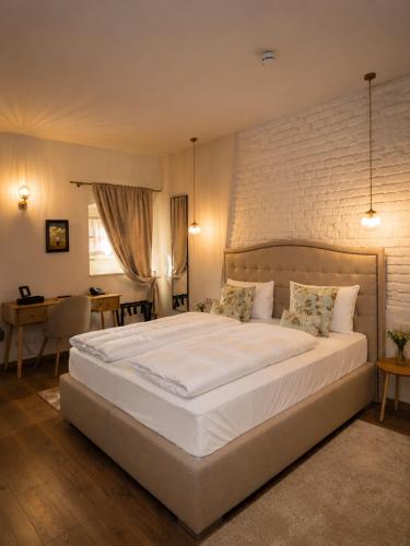 a bedroom with a large white bed with a brick wall at Generalis Wine Hotel in Tokaj