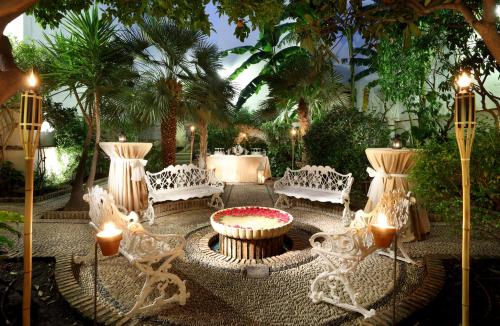 a patio with white furniture and a table and palm trees at Eurostars Conquistador in Córdoba