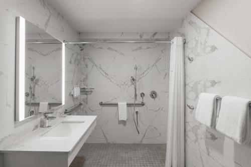 a white bathroom with a shower and a sink at Days Inn by Wyndham Mandan Bismarck Area in Mandan