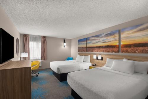 a hotel room with two beds and a flat screen tv at Days Inn by Wyndham Mandan Bismarck Area in Mandan