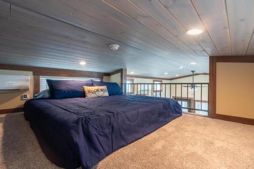 a bedroom with a large bed with a blue comforter at Deers Den River- Luxury Tiny Home on River in Bryson City