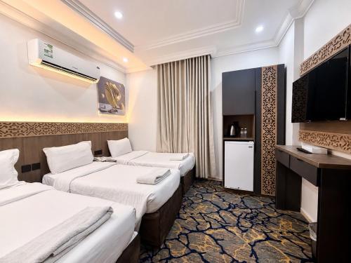 a hotel room with two beds and a television at Luluat Al Badaie Hotel in Mecca