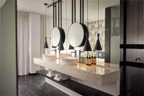 a bathroom with three sinks and two mirrors at Van der Valk Zaltbommel-A2 in Zaltbommel