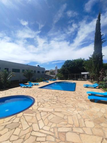 a pool with blue lounge chairs and a building at Hotel Rezende in Lambari