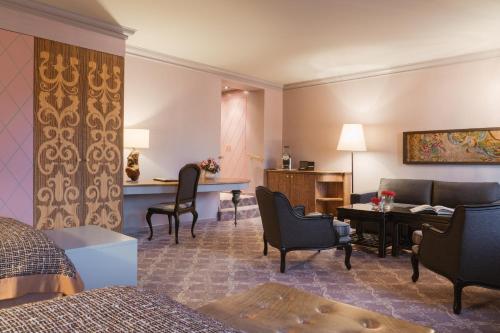 a hotel room with a bed and a desk and chairs at Carlton Hotel St Moritz - The Leading Hotels of the World in St. Moritz
