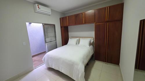 a bedroom with a white bed and a window at Casa Completa e Confortável para sua Estadia in Ribeirão Preto