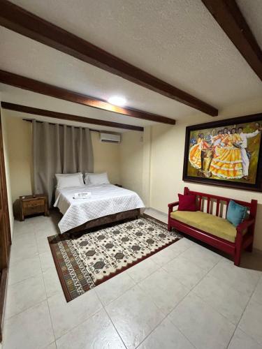 a bedroom with a bed and a couch and a painting at Hotel La Casona Del Valle in Valledupar