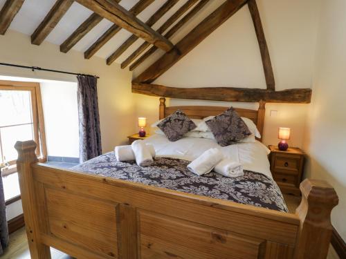 a bedroom with a large wooden bed with pillows at Bwthyn Y Wennol in Llanddulas