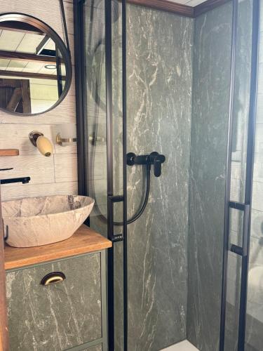 a shower with a glass door next to a sink at Entre ciel et champs in Capendac