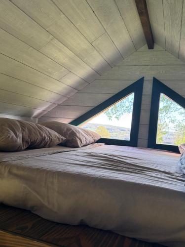 a large bed in a room with two windows at Entre ciel et champs in Capendac