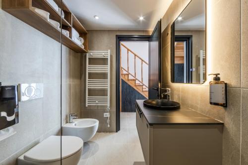 a bathroom with a sink and a toilet and a mirror at Muraga Villas by PikHost in Tirana