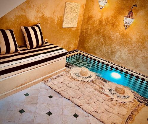 a room with a pool with a bench and a table at Riad Kimee in Marrakesh