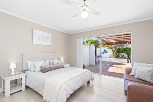 a white bedroom with a bed and a couch at Ravens 9A in Bloubergstrand