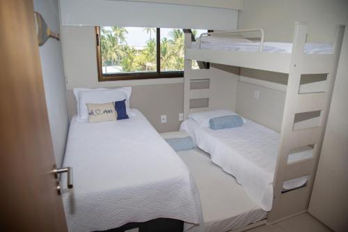 two bunk beds in a small room with a window at Flat Resort Beira Mar Porto de Galinhas in Ipojuca