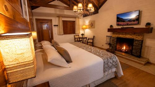 a bedroom with a large bed and a fireplace at Pousada Charme da Montanha in Monte Verde