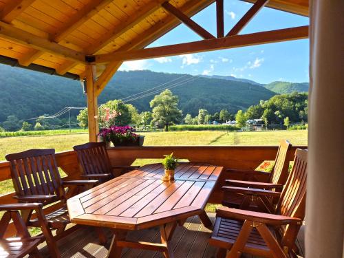 a wooden table and chairs on a deck with a view at Kućica na jezeru in Jezero