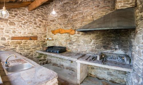 a stone kitchen with a stove and a sink at L'Oustal del Sully - Villa d'exception avec piscine, proche lac de Pareloup in Prades-Salars