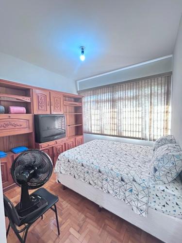 a bedroom with a bed and a television and a chair at Hospedagem da Renata in Salto