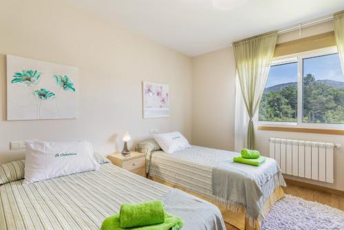 a bedroom with two beds and a window at Os Cabaleiros in Mos