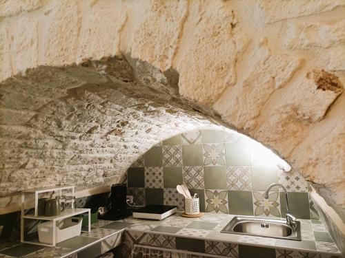 a kitchen with a sink and a stone wall at La Carruba in Ceglie Messapica