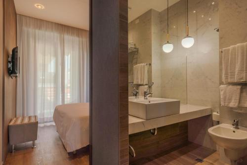 a bathroom with a sink and a bed and a mirror at AmbientHotels Panoramic in Rimini