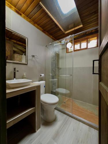 a bathroom with a toilet and a glass shower at Cabañas Campestres Yugos in Sutatausa
