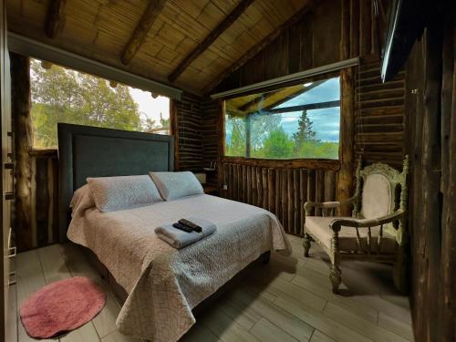 a bedroom with a bed and a chair and a window at Cabañas Campestres Yugos in Sutatausa