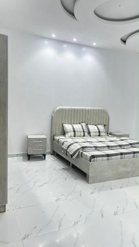 a white bedroom with a bed and a night stand at شقه ارضيه in Hail