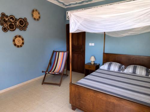 a bedroom with a bed with a canopy and a chair at Chambre Bleu - Coco Room Nosy-Be in Nosy Be