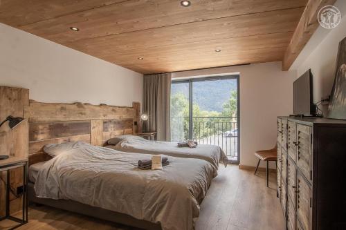 a bedroom with two beds and a large window at Chalet de l'epigny in Bellecombe