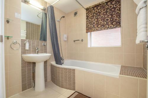 a bathroom with a sink and a tub and a toilet at Revado Hotel, Norwich City Centre in Norwich