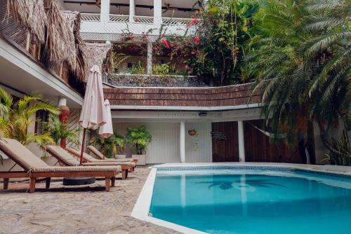 a swimming pool with chairs and an umbrella next to a building at Tranquilseas Boutique Eco Resort & Dive Center in West End
